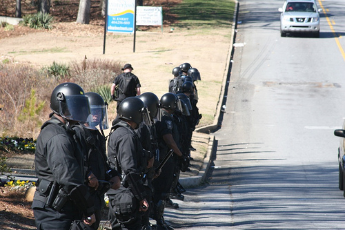 Police in crowd-control gear protect the CoS